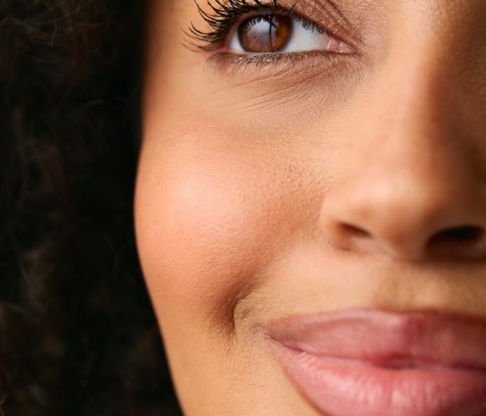 close up studio portrait showing half face of smiling natural woman close up studio portrait showing half face of smiling natural woman